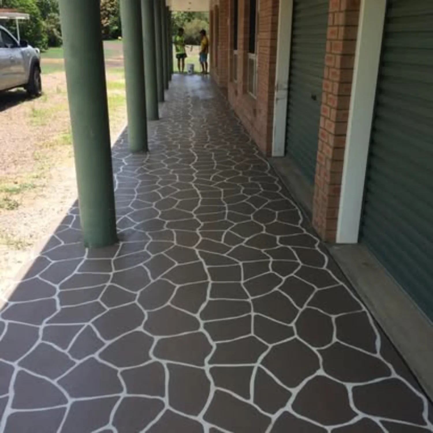 Decorative grey stencilled concrete extension by Mark Holstein Concreting in Hervey Bay, connecting the front doorway and garage spaces.