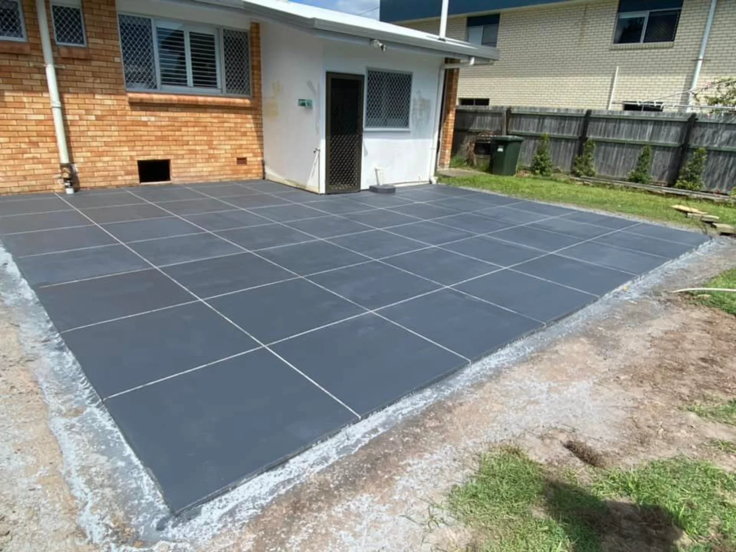 Decorative dark grid patterned concrete patio installed by Mark Holstein Concreting