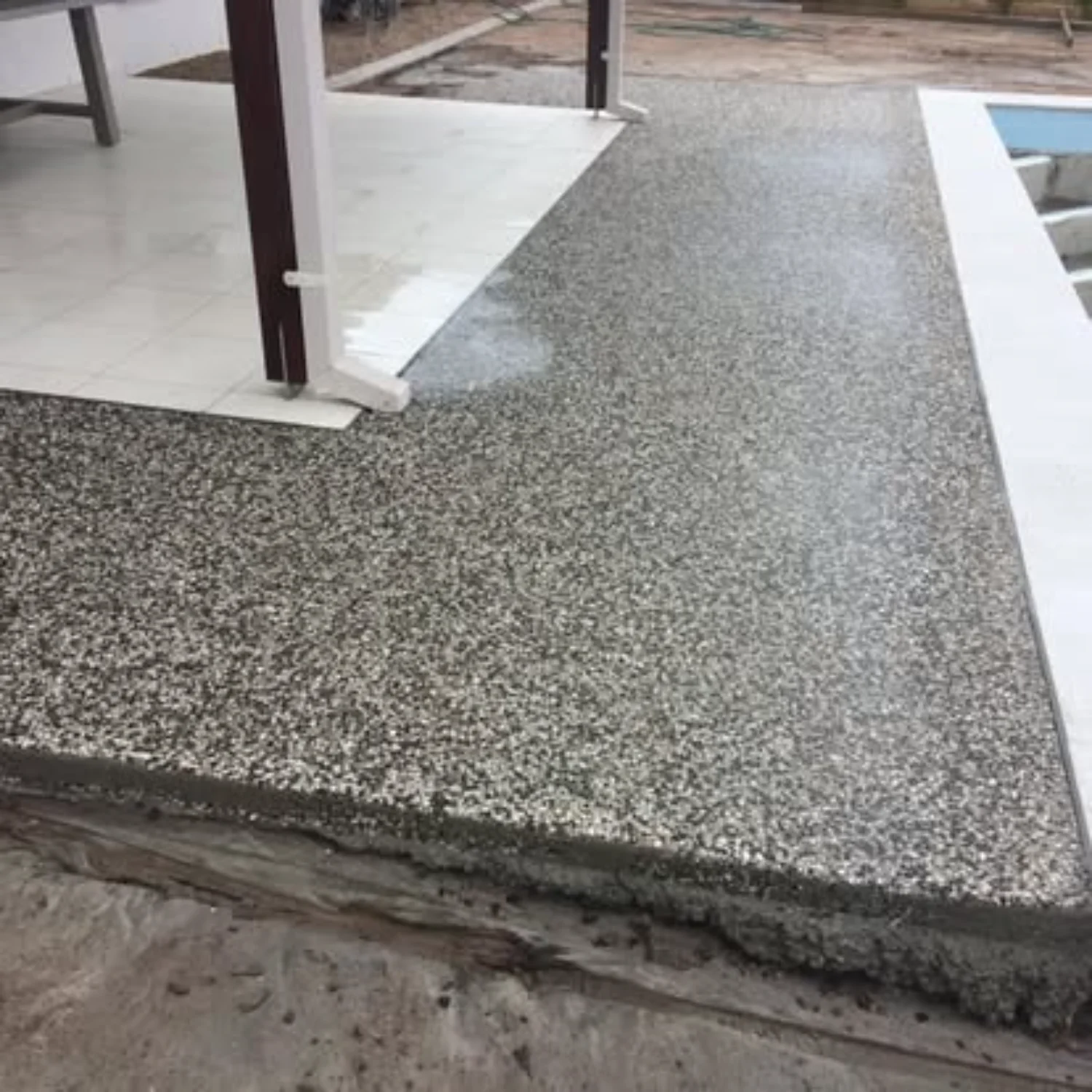 Exposed aggregate concrete extension by Mark Holstein Concreting, connecting a patio and pool area in Hervey Bay